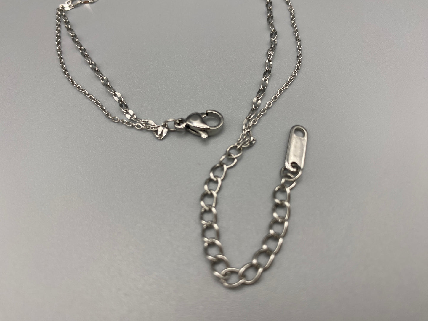 Aurora Twin Chain Bracelet in silver with a sophisticated twin chain design, adorned with sparkling zirconia gemstones. Waterproof and measures 18 cm with a 3 cm extender for adjustable fit.”
