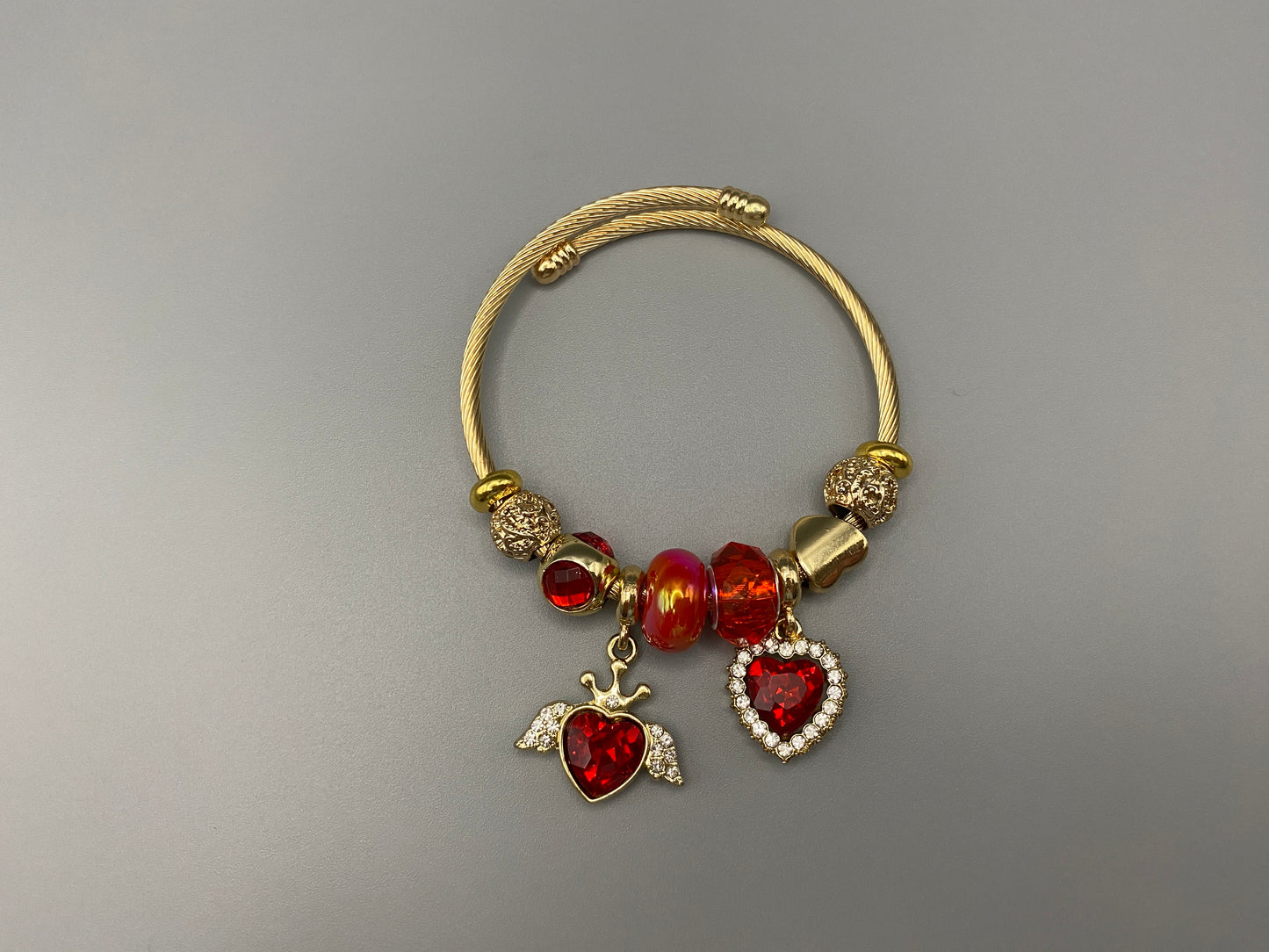 Belle Red Charm Bracelet with gold-plated finish, featuring heart-cut crystals and rhinestones. Made from durable stainless steel with playful charms and micro insert inlay technology.”