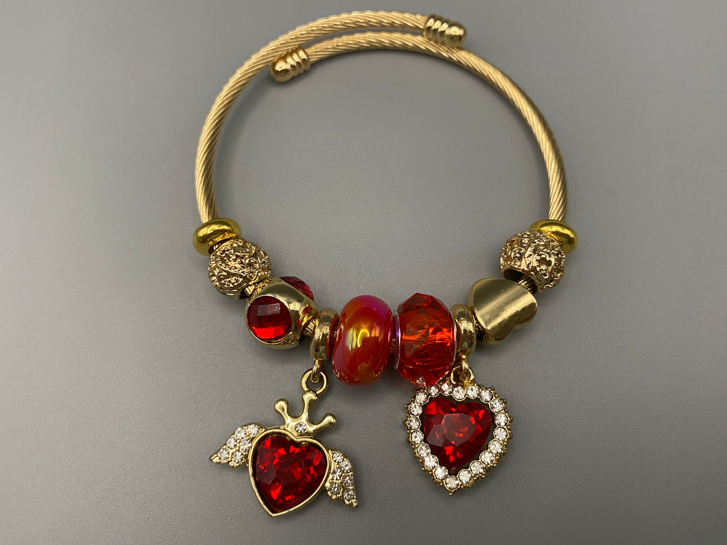 Belle Red Charm Bracelet with gold-plated finish, featuring heart-cut crystals and rhinestones. Made from durable stainless steel with playful charms and micro insert inlay technology.”
