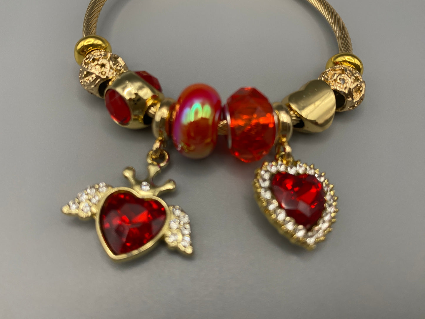 Belle Red Charm Bracelet with gold-plated finish, featuring heart-cut crystals and rhinestones. Made from durable stainless steel with playful charms and micro insert inlay technology.”