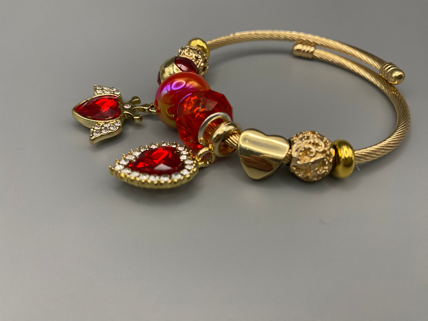Belle Red Charm Bracelet with gold-plated finish, featuring heart-cut crystals and rhinestones. Made from durable stainless steel with playful charms and micro insert inlay technology.”