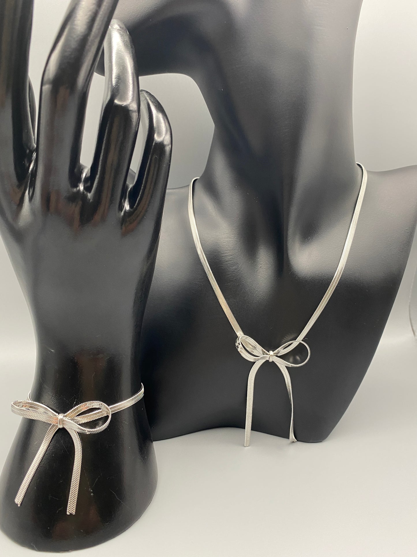 “Celest Angel Bow Bracelet in Silver featuring a delicate bow design, made of stainless steel for durability and tarnish resistance. Measures 18 cm with a 3 cm extender for adjustable fit.”