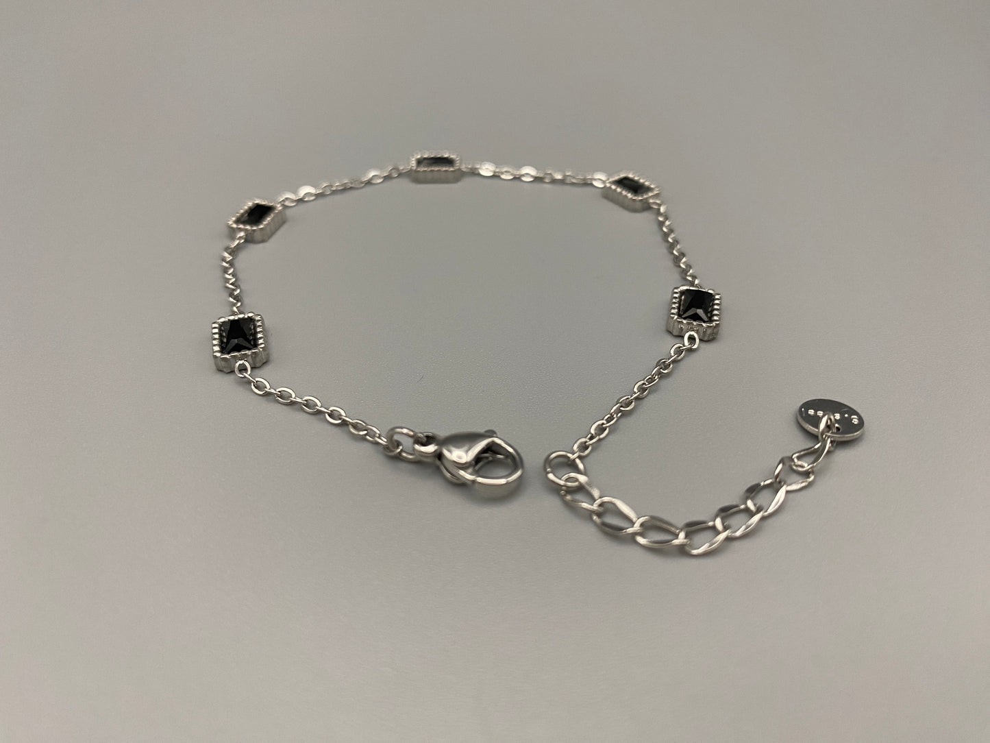 “Clarissa Bracelet in silver with black zircon inset stones, featuring a luxurious silver plating and adjustable length of 17.5 cm with a 2 cm extension. Durable construction ensures long-lasting wear and tarnish resistance.”