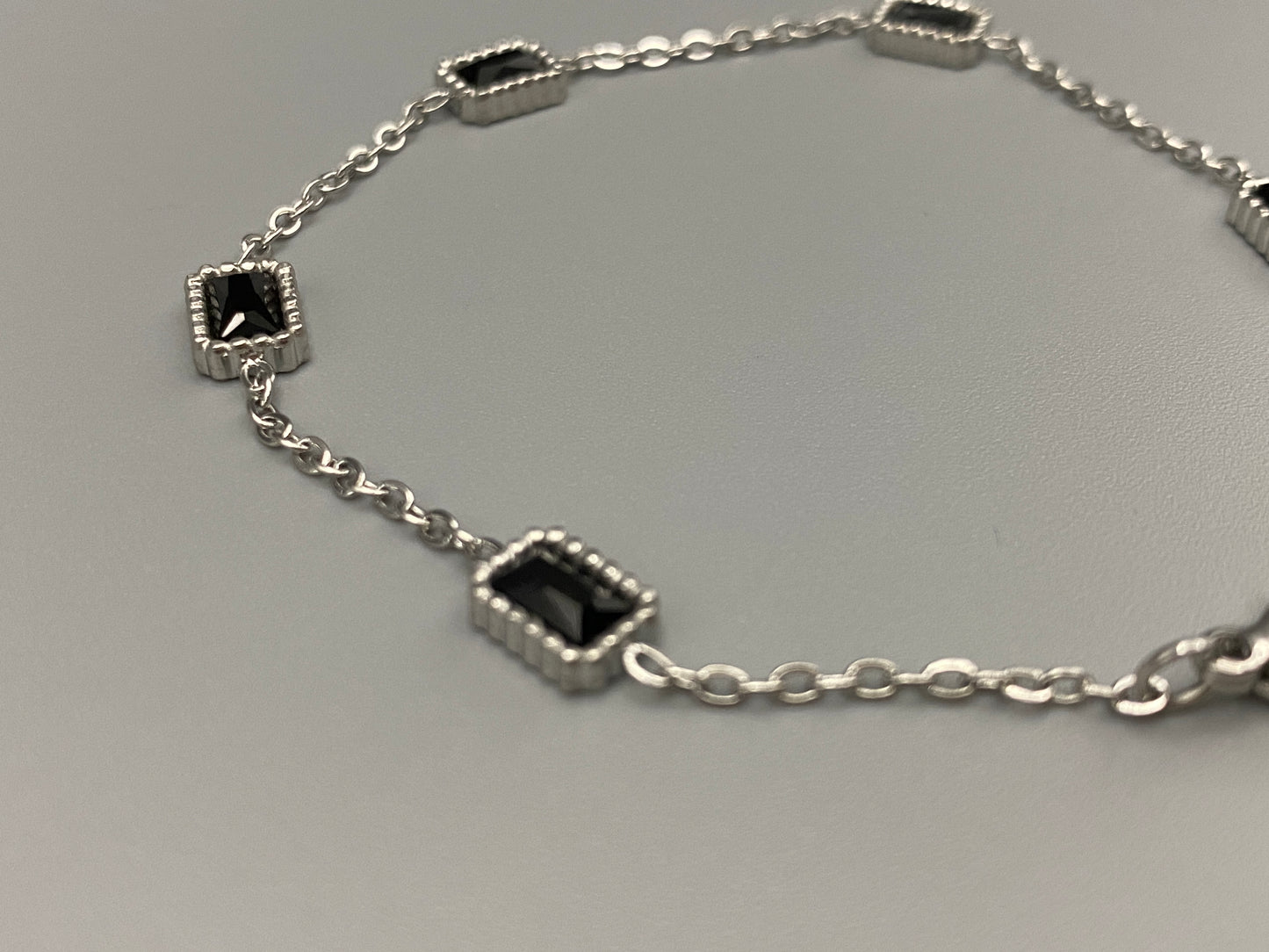 “Clarissa Bracelet in silver with black zircon inset stones, featuring a luxurious silver plating and adjustable length of 17.5 cm with a 2 cm extension. Durable construction ensures long-lasting wear and tarnish resistance.”