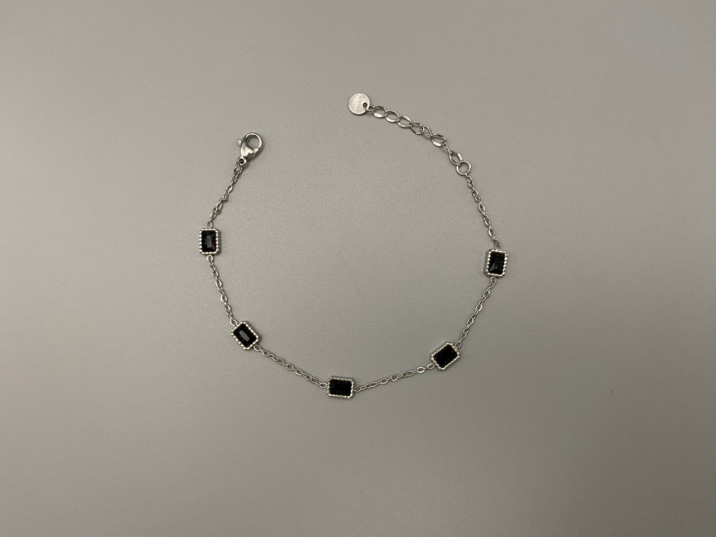 “Clarissa Bracelet in silver with black zircon inset stones, featuring a luxurious silver plating and adjustable length of 17.5 cm with a 2 cm extension. Durable construction ensures long-lasting wear and tarnish resistance.”