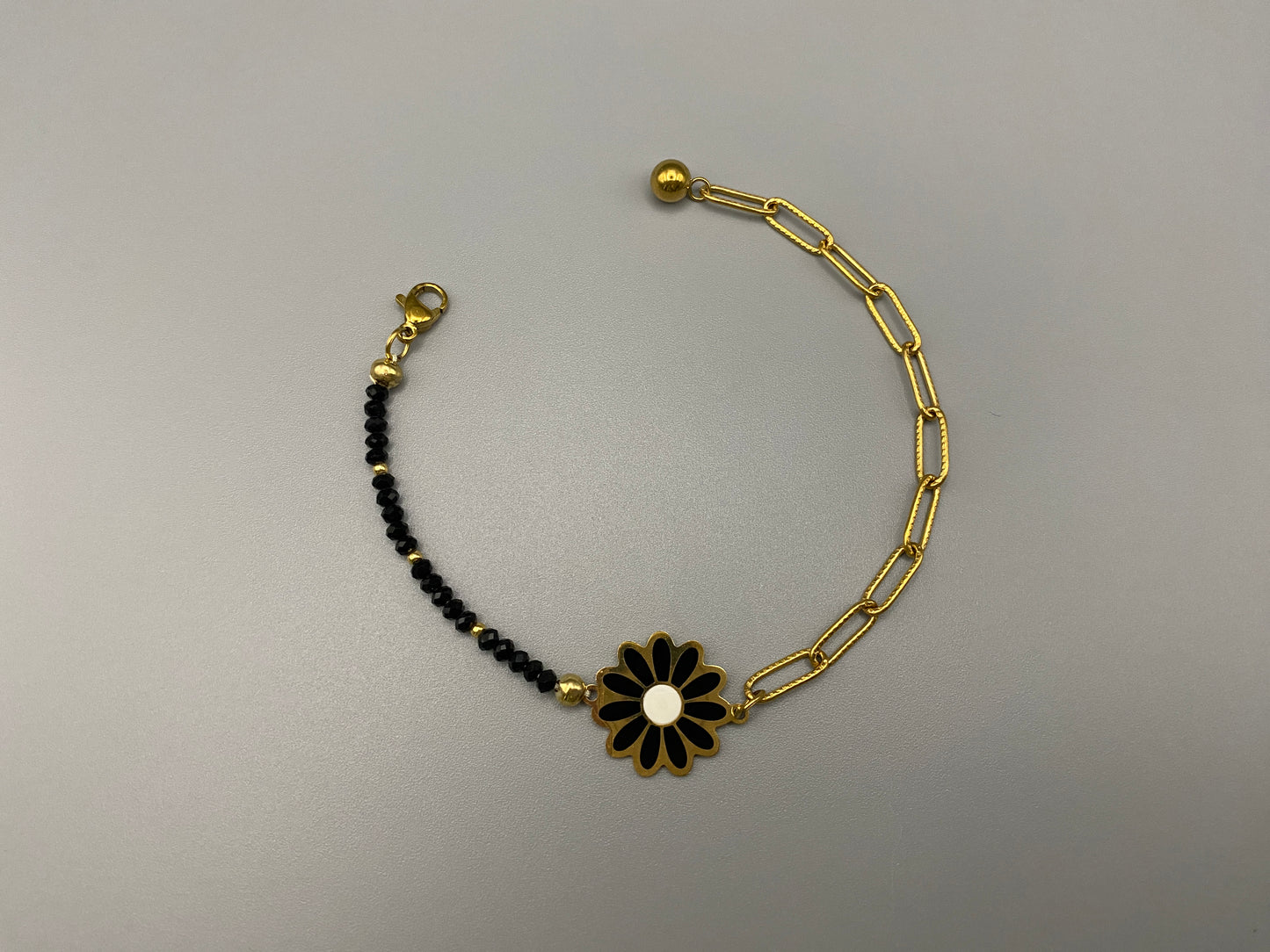 “Daisy Chain Bead Bracelet in black, crafted from stainless steel with 18K gold plating. Features a daisy flower pattern with crystal and rhinestone accents. Eco-friendly, nickel and lead-free, safe for sensitive skin.”
