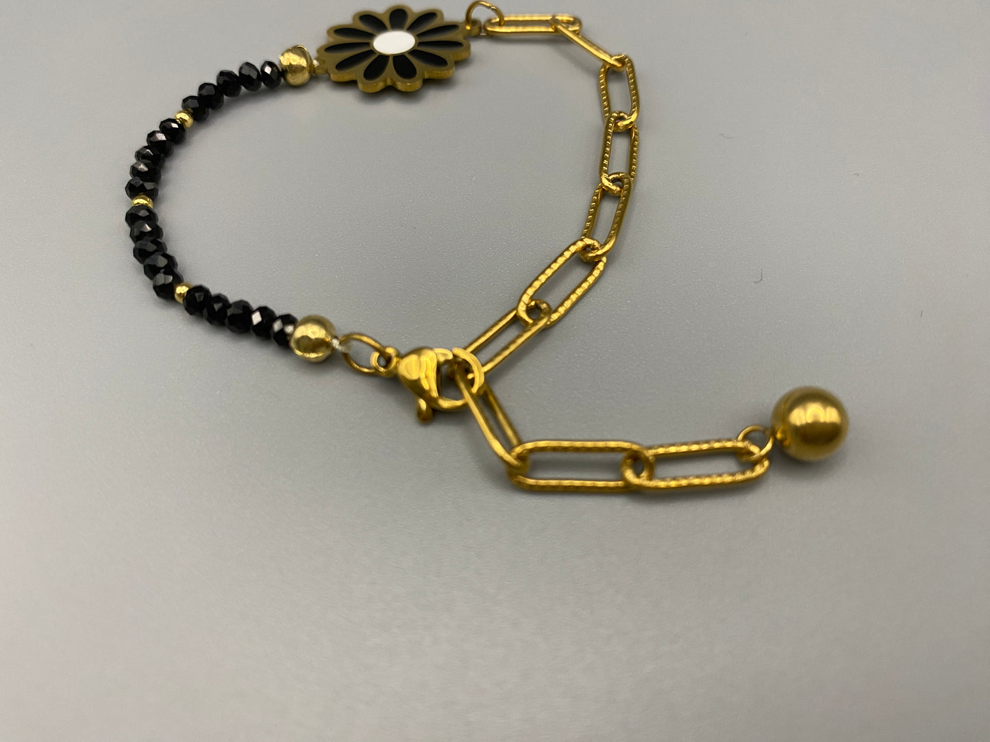 Daisy Chain Bead Bracelet in black, crafted from stainless steel with 18K gold plating. Features a daisy flower pattern with crystal and rhinestone accents. Eco-friendly, nickel and lead-free, safe for sensitive skin.”