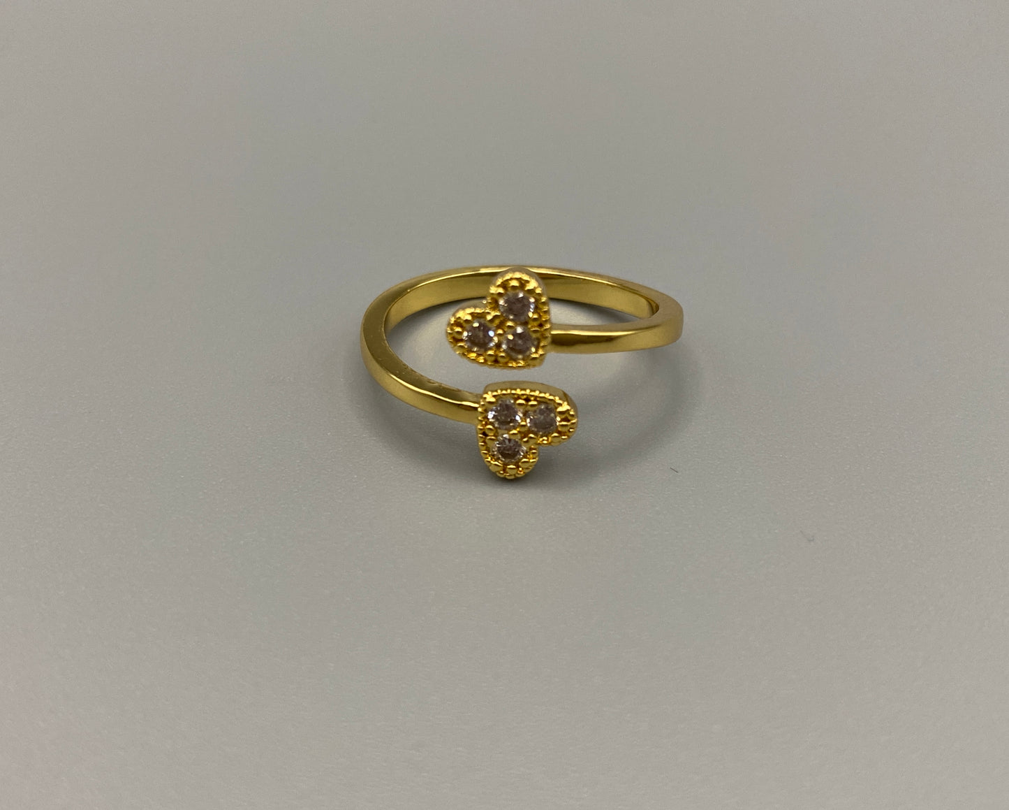 Dove Double Heart Adjustable Ring Gold: This beautiful ring features a double heart design, each adorned with sparkling zirconia stones. The elegant design, combined with 18k gold plating, creates a romantic and timeless look. The ring is non-tarnish, waterproof, nickel-free, and non-fading, ensuring it maintains its shine and is safe for sensitive skin. The adjustable size provides a comfortable fit for various finger sizes.
