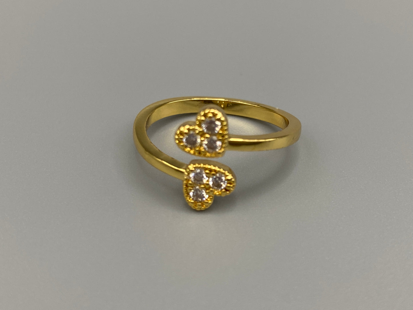 Dove Double Heart Adjustable Ring Gold: This beautiful ring features a double heart design, each adorned with sparkling zirconia stones. The elegant design, combined with 18k gold plating, creates a romantic and timeless look. The ring is non-tarnish, waterproof, nickel-free, and non-fading, ensuring it maintains its shine and is safe for sensitive skin. The adjustable size provides a comfortable fit for various finger sizes.