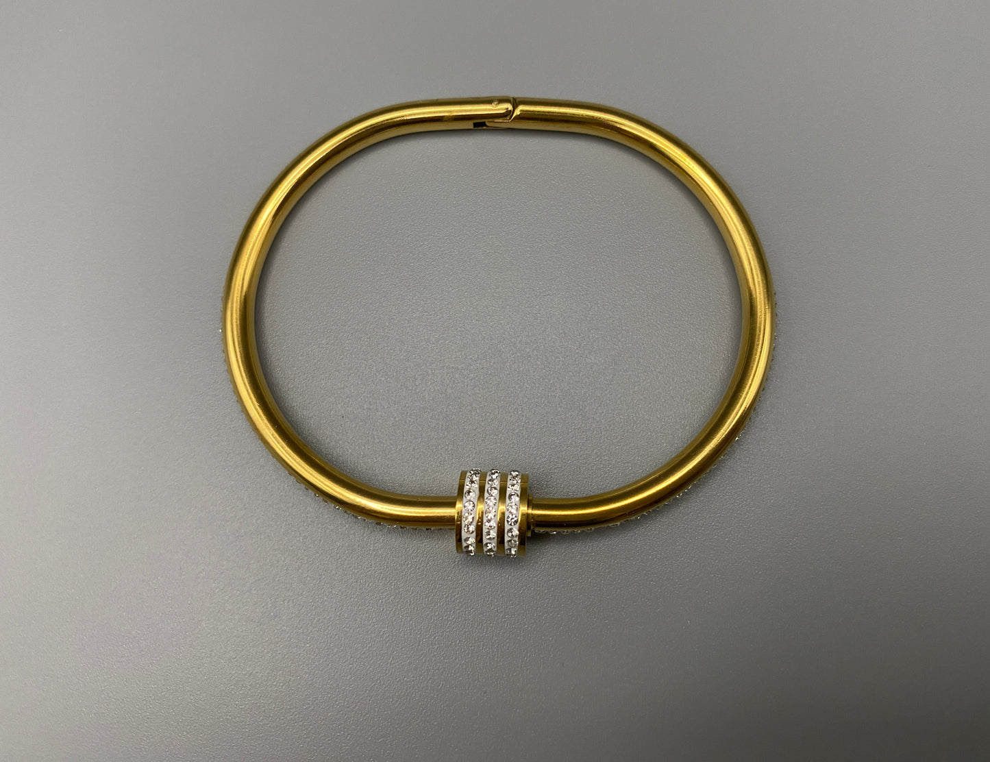 “Eclipse Encrusted Bangle Bracelet in gold with an encrusted gem inlay, featuring 18K gold plating and a thread open and close mechanism for easy adjustment. Made from high-quality materials for long-lasting wear.”