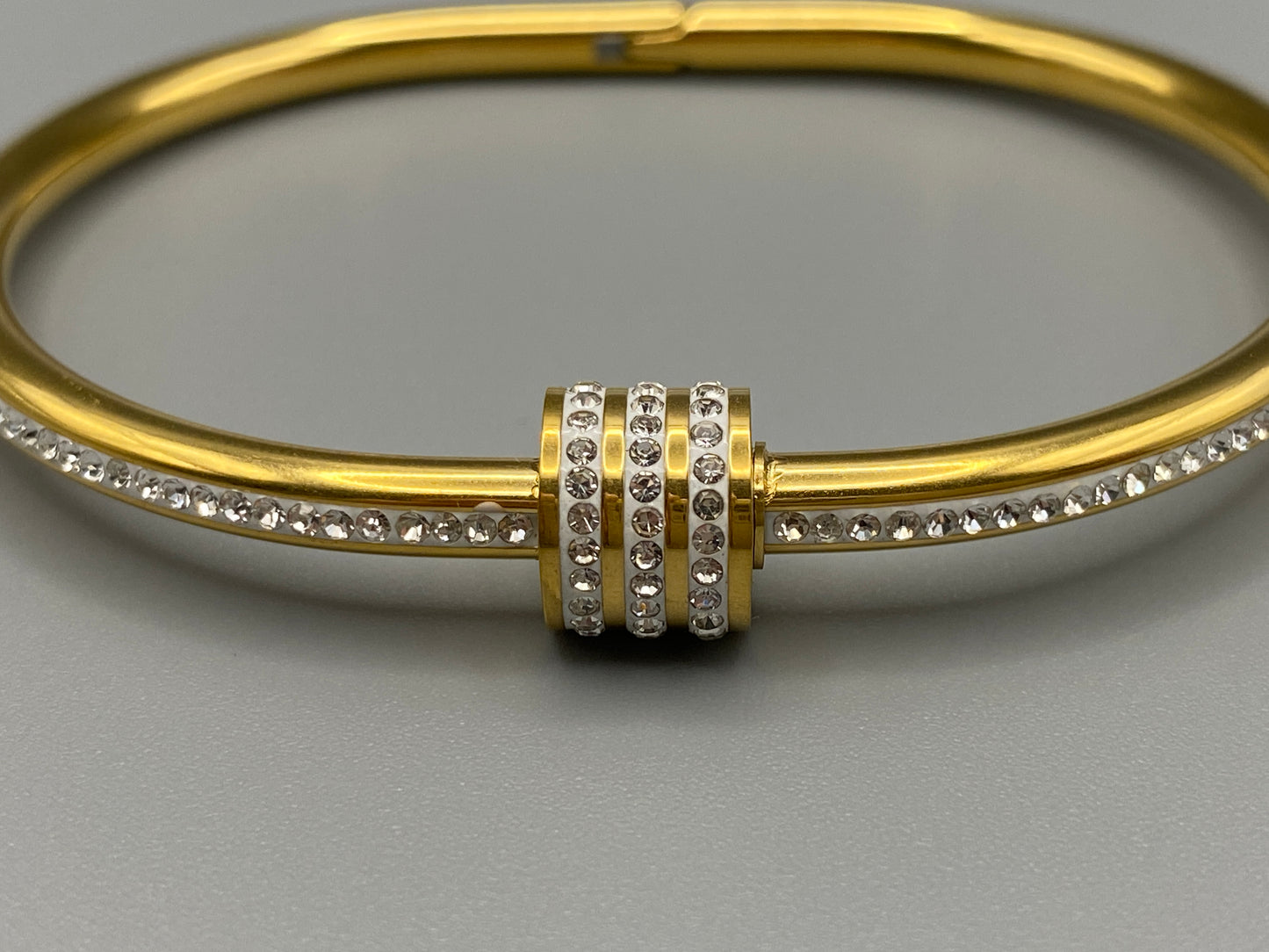 “Eclipse Encrusted Bangle Bracelet in gold with an encrusted gem inlay, featuring 18K gold plating and a thread open and close mechanism for easy adjustment. Made from high-quality materials for long-lasting wear.”