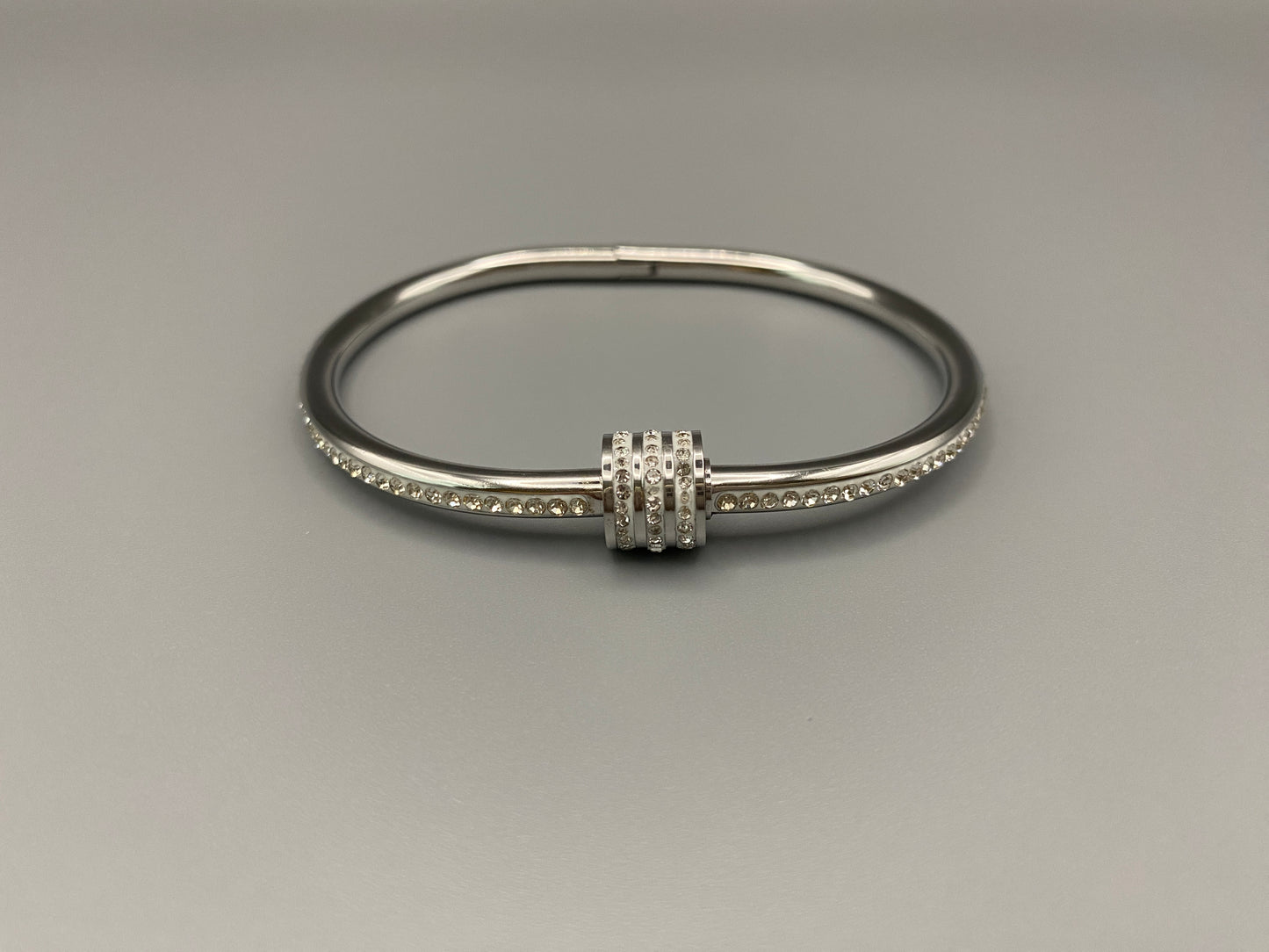 “Eclipse Encrusted Bangle Bracelet in silver with an encrusted gem inlay, featuring silver plating and a thread open and close mechanism for easy adjustment. Made from high-quality materials for long-lasting wear.”
