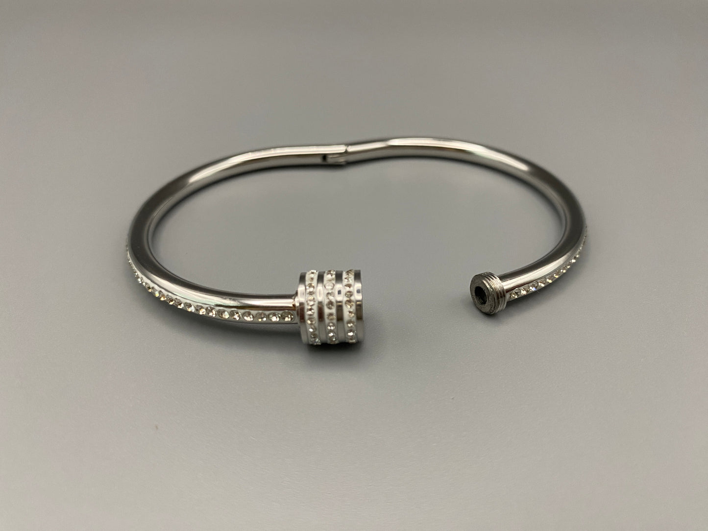 “Eclipse Encrusted Bangle Bracelet in silver with an encrusted gem inlay, featuring silver plating and a thread open and close mechanism for easy adjustment. Made from high-quality materials for long-lasting wear.”