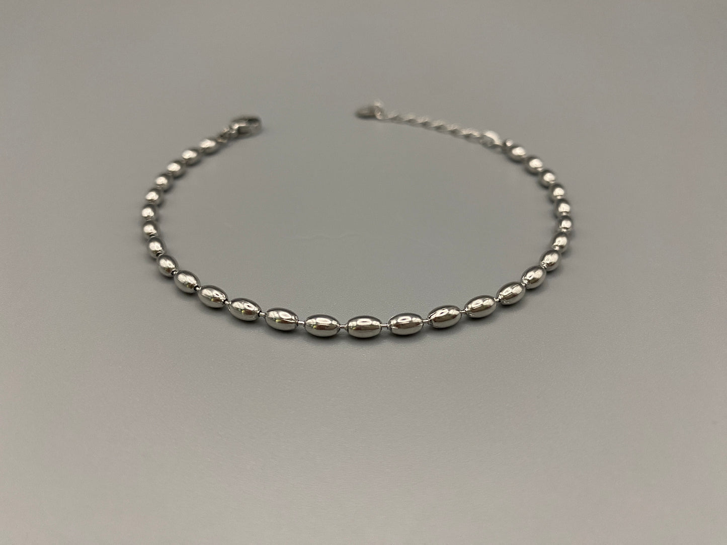 “Elliptica Bracelet in silver with connected oval-shaped links, featuring a modern and sophisticated design. Made from durable stainless steel with a silver finish. Measures 17 cm with a 3 cm extender for adjustable fit.”