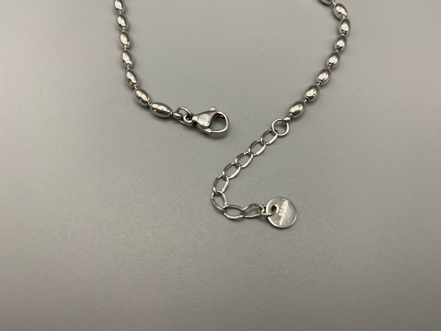 “Elliptica Bracelet in silver with connected oval-shaped links, featuring a modern and sophisticated design. Made from durable stainless steel with a silver finish. Measures 17 cm with a 3 cm extender for adjustable fit.”
