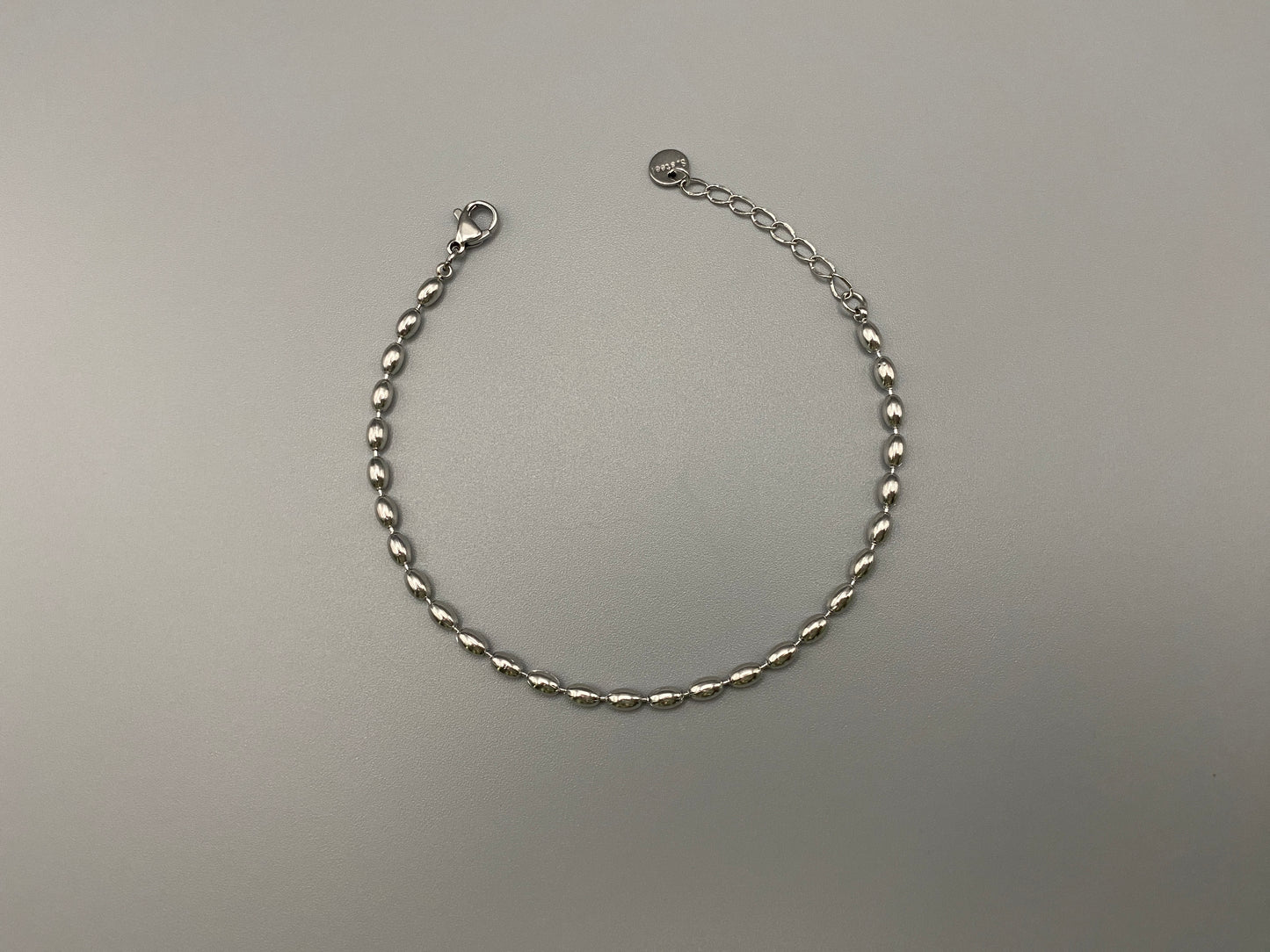 “Elliptica Bracelet in silver with connected oval-shaped links, featuring a modern and sophisticated design. Made from durable stainless steel with a silver finish. Measures 17 cm with a 3 cm extender for adjustable fit.”