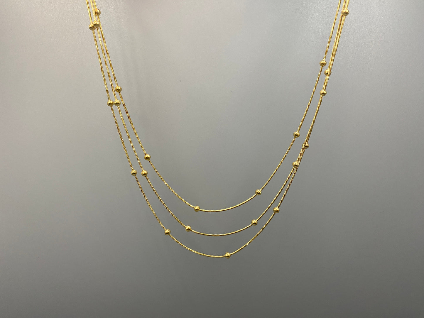 Freya Tri-Chain Bead Necklace Gold. Elegant tri-chain design with bead accents. 18k gold plated, PVD plated for durability. Adjustable length: 40 cm + 5 cm extender. Versatile for layering or solo wear.