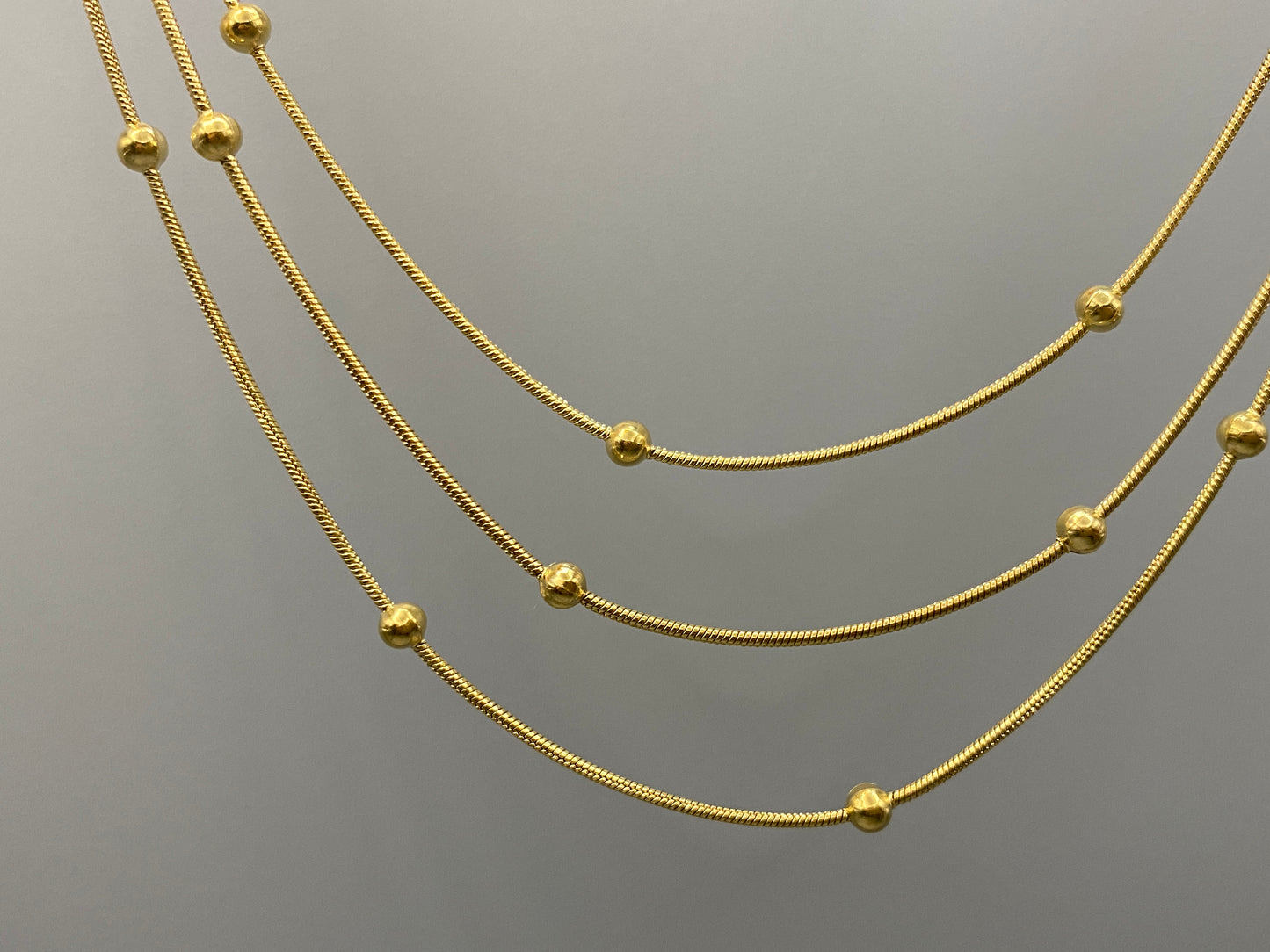 Freya Tri-Chain Bead Necklace Gold. Elegant tri-chain design with bead accents. 18k gold plated, PVD plated for durability. Adjustable length: 40 cm + 5 cm extender. Versatile for layering or solo wear.