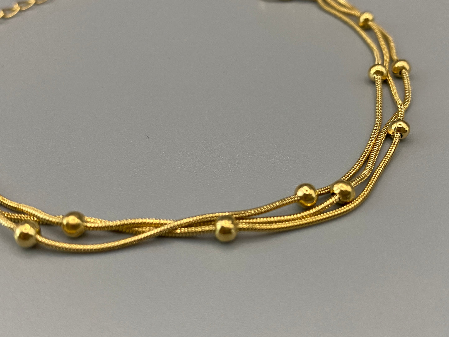 Freya Tri-Chained Bead Bracelet in gold with three delicate chains and evenly spaced small beads. 18K gold plated, made from durable stainless steel with PVD plating. Measures 18 cm with a 3 cm extender for adjustable fit.”