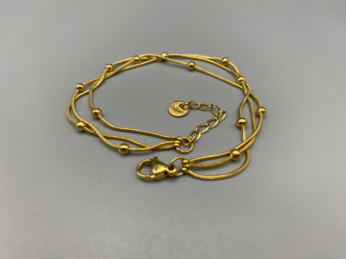 Freya Tri-Chained Bead Bracelet in gold with three delicate chains and evenly spaced small beads. 18K gold plated, made from durable stainless steel with PVD plating. Measures 18 cm with a 3 cm extender for adjustable fit.”