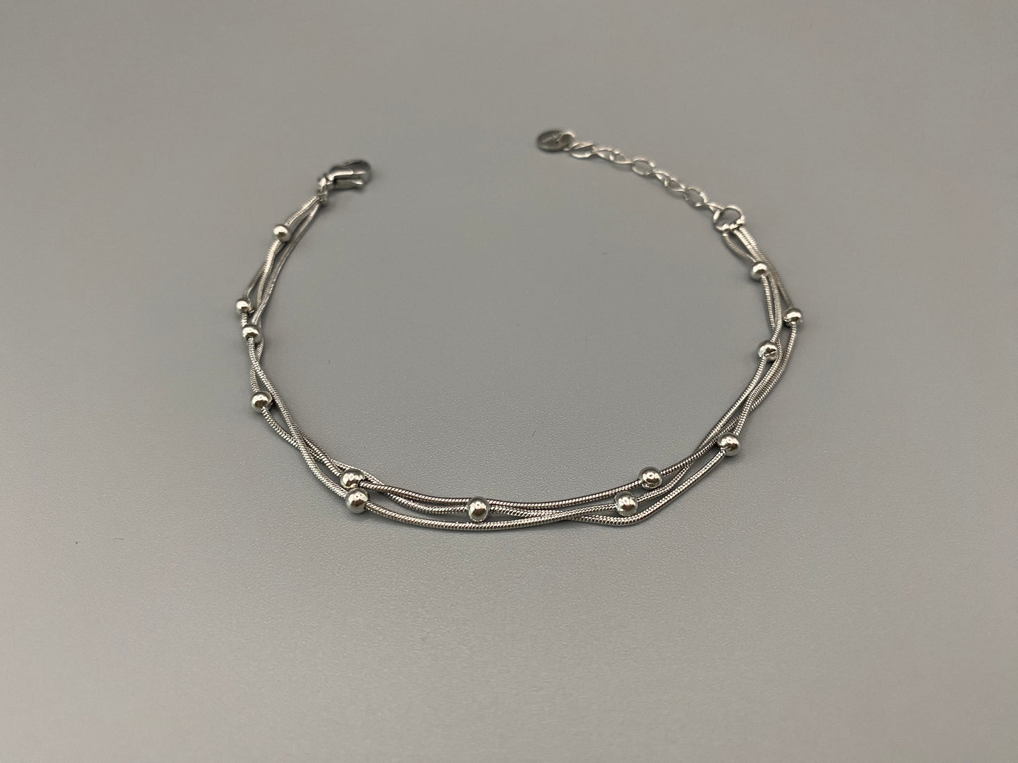 “Freya Tri-Chained Bead Bracelet in silver with three delicate chains and evenly spaced small beads. Silver plated, made from durable stainless steel with PVD plating. Measures 18 cm with a 3 cm extender for adjustable fit.”