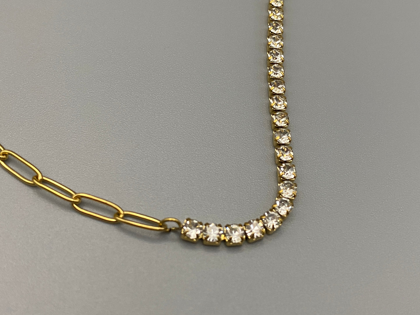 “Gemma Necklace in gold with iced-out zircon paperclip chain, crafted from tarnish-free stainless steel and plated with 18K gold. Measures 45 cm in length with a 5 cm adjustment. Waterproof and perfect for daily wear or special occasions.”
