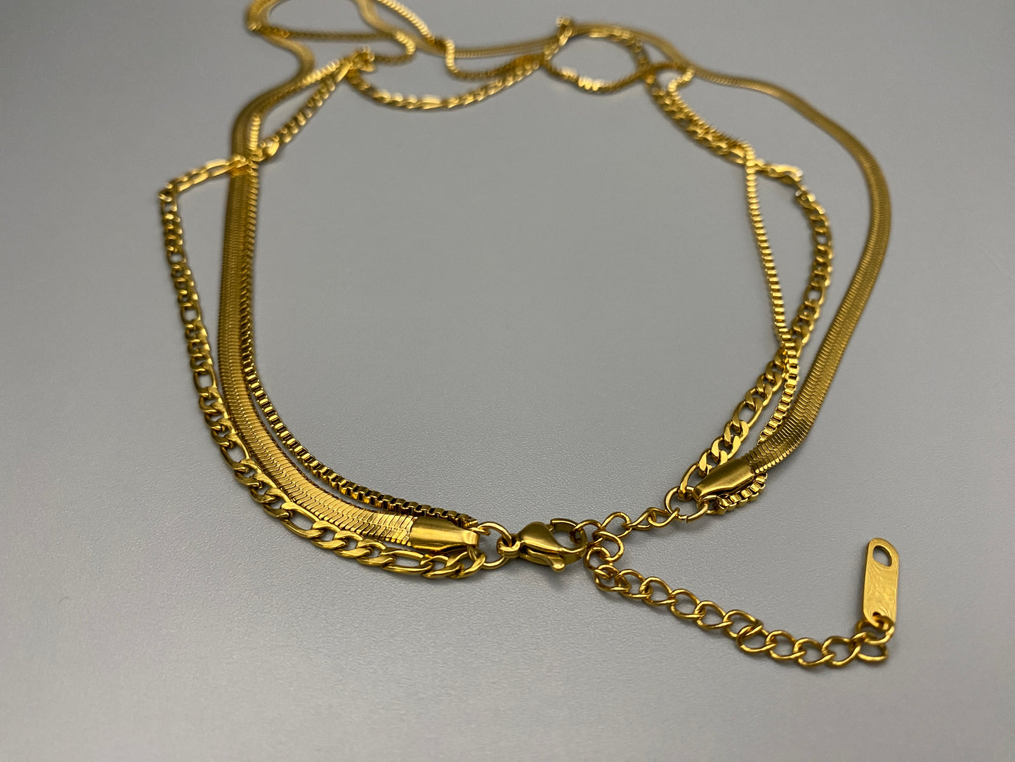 Gina Three Layered Gold Chain Necklace. Three delicate chains layered for a sophisticated look. 18k gold plated, PVD plated for durability. Stainless steel, corrosion-resistant. Adjustable length: 40 cm + 5 cm extender. Versatile for casual and formal wear.