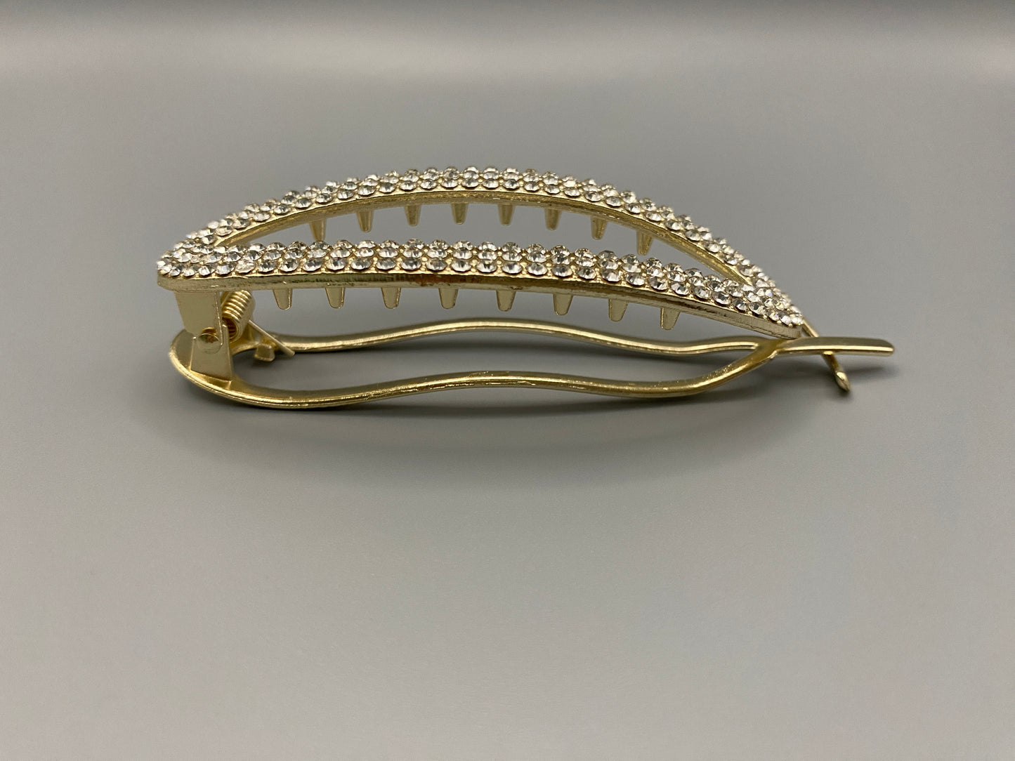 GlitzGrip Hollow Gold Hair Clip featuring a hollow oval design with “sparkling zircon gems, measuring 9.5 cm in length. Elegant and durable, perfect for various hairstyles.”