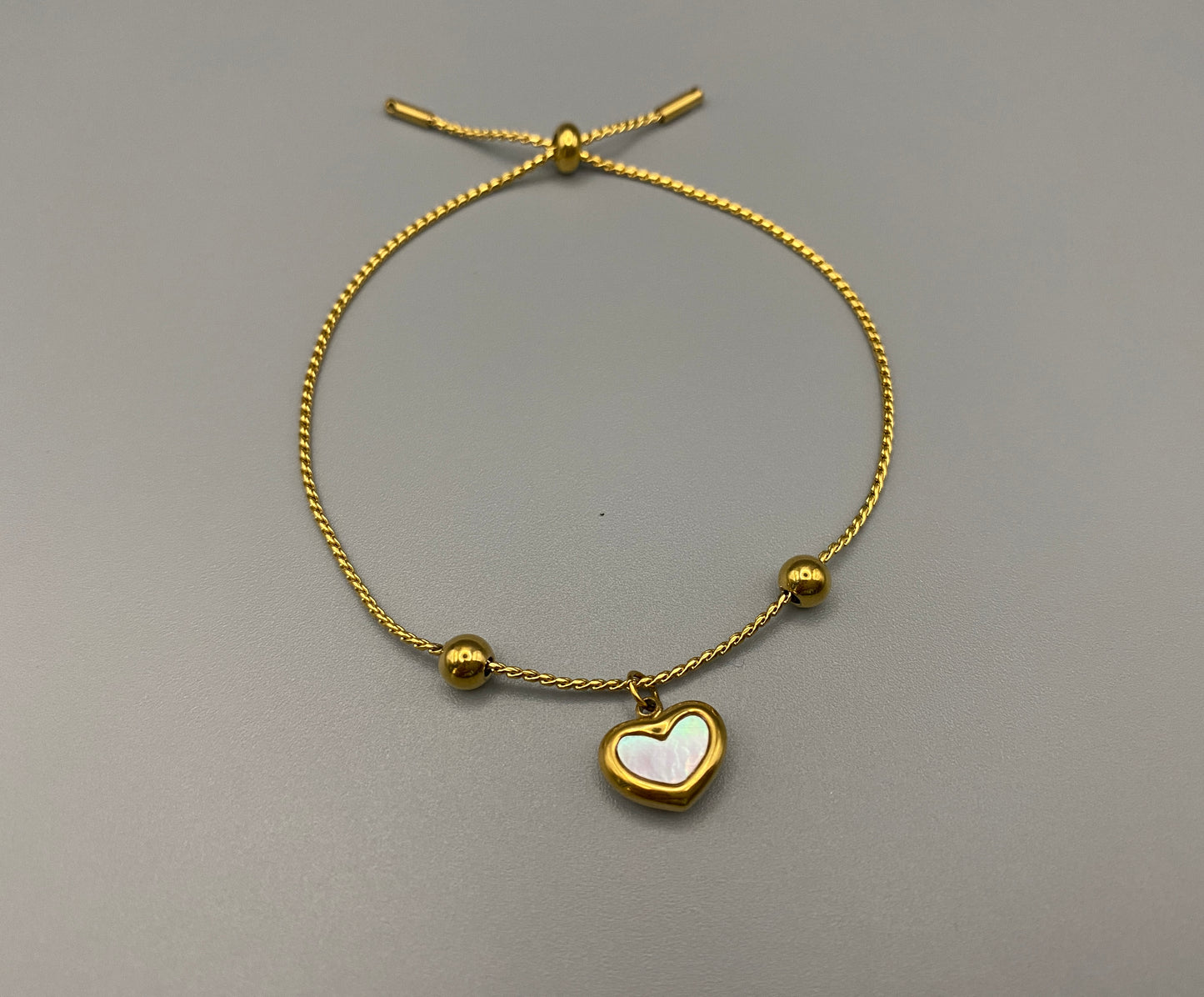 “Helena Heart Bracelet in gold with a white shell heart pendant, crafted from high-quality stainless steel and plated with 18K gold. Adjustable, waterproof, tarnish-free, and environmentally friendly.”