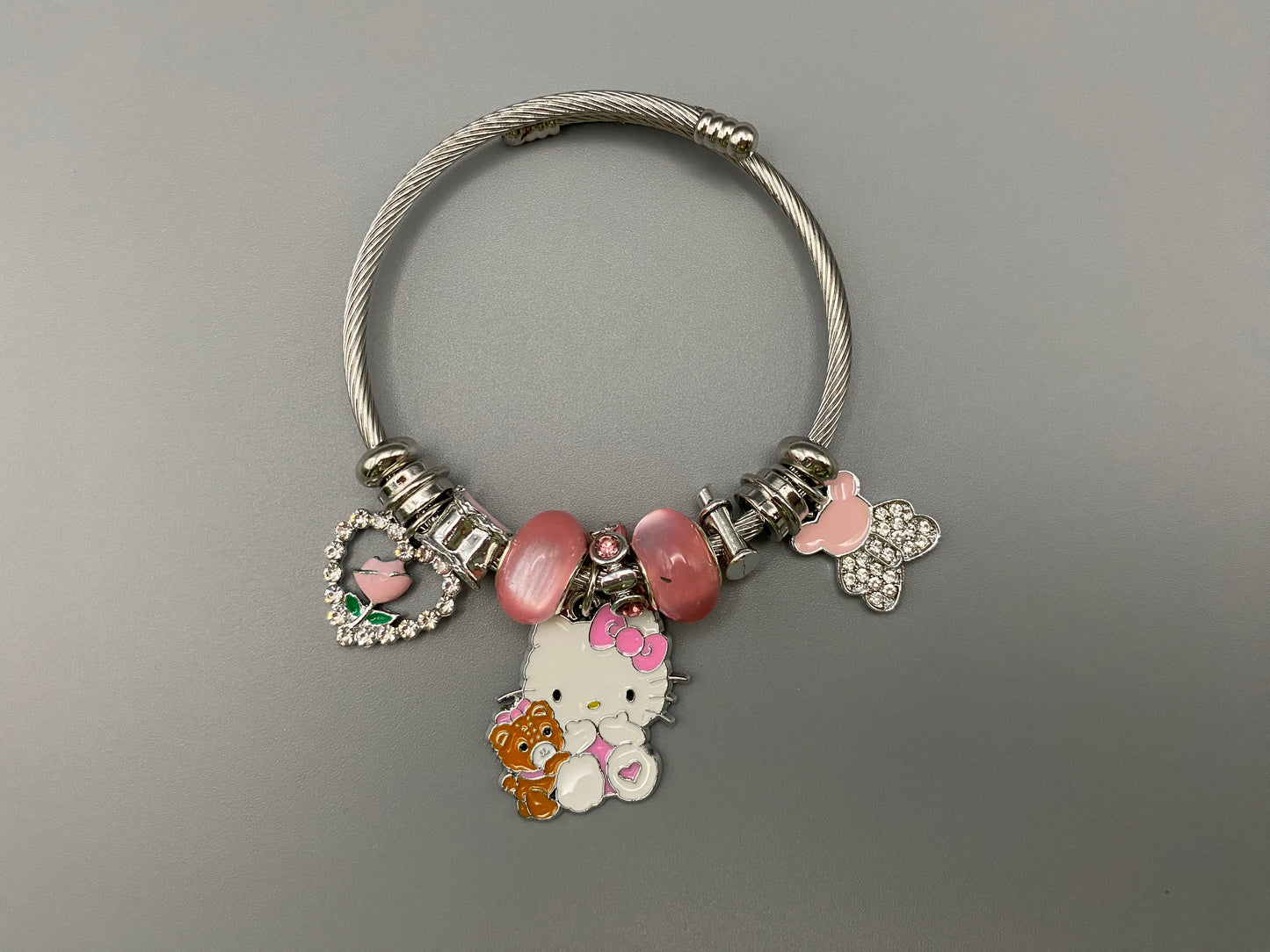 Kitty Cartoon Character Bracelet in pink with stainless steel bangles, adorned with alloy charms, crystals, and glass beads. Features a charm with pink accents, combining playful elegance and sophistication.”