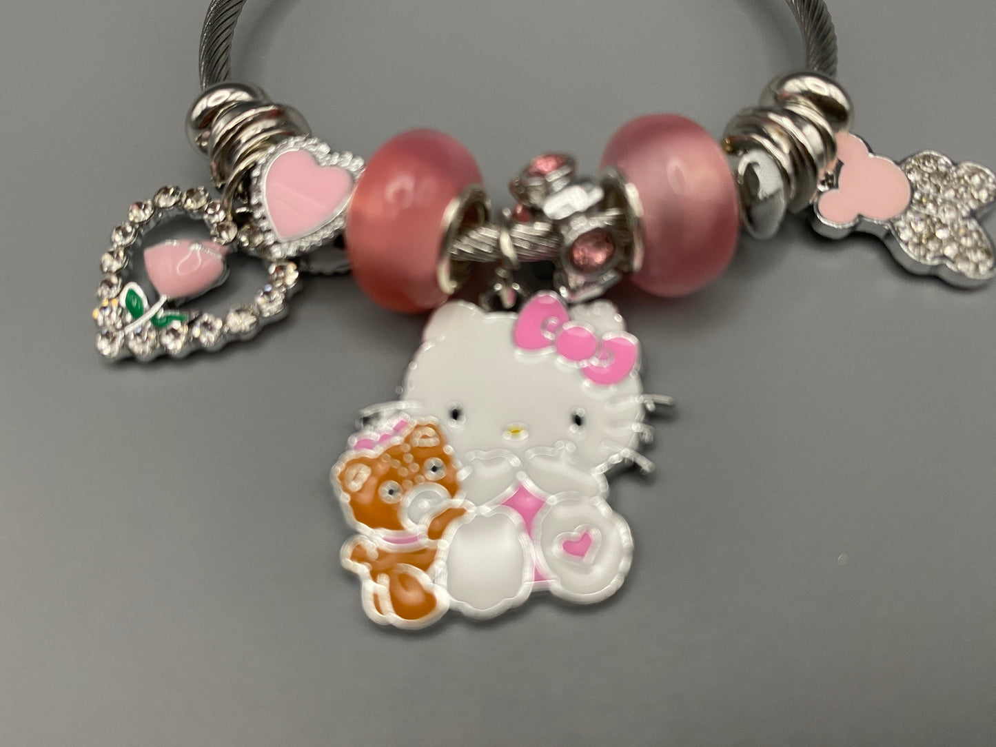 Kitty Cartoon Character Bracelet in pink with stainless steel bangles, adorned with alloy charms, crystals, and glass beads. Features a charm with pink accents, combining playful elegance and sophistication.”