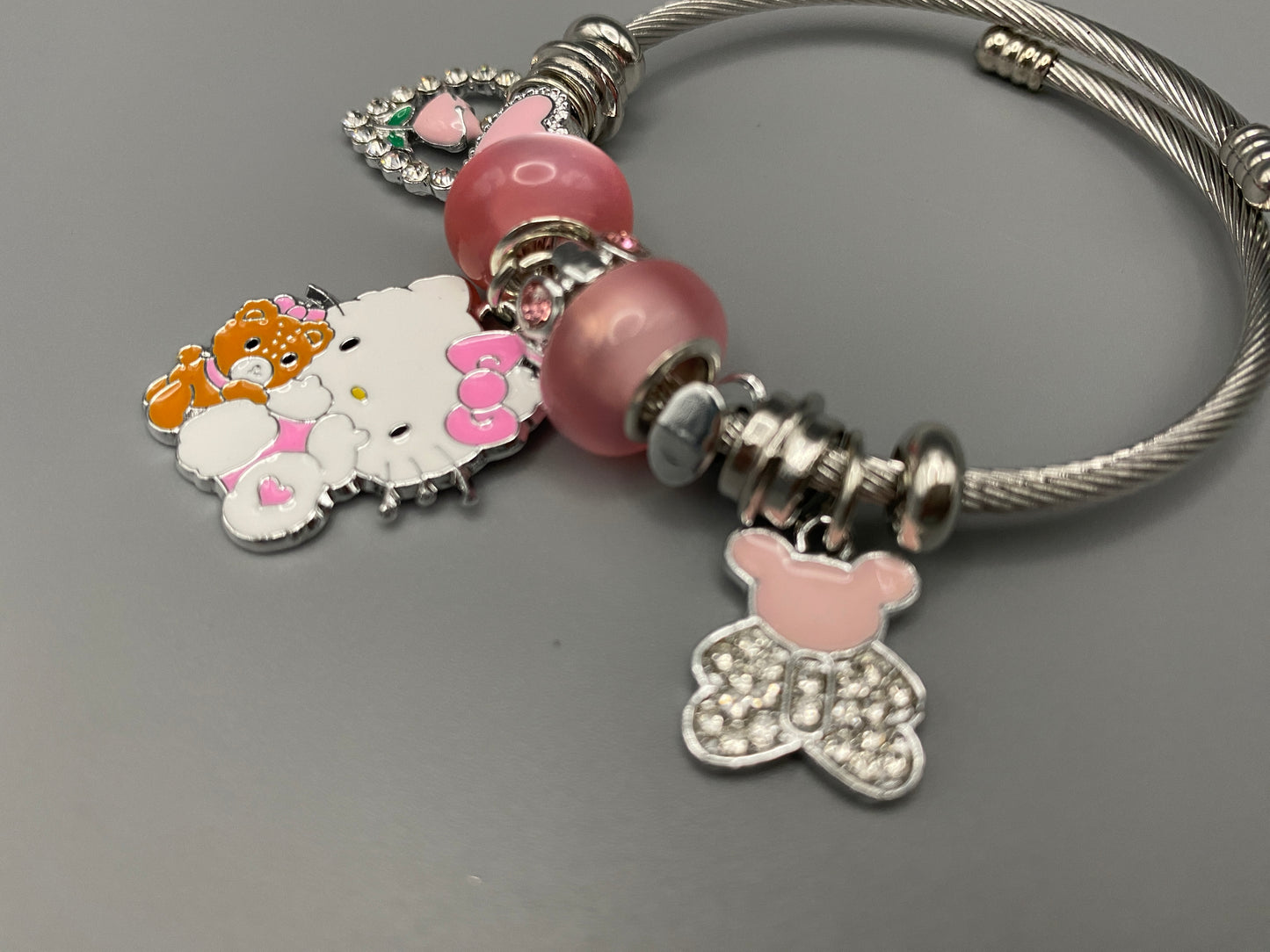 Kitty Cartoon Character Bracelet in pink with stainless steel bangles, adorned with alloy charms, crystals, and glass beads. Features a charm with pink accents, combining playful elegance and sophistication.”