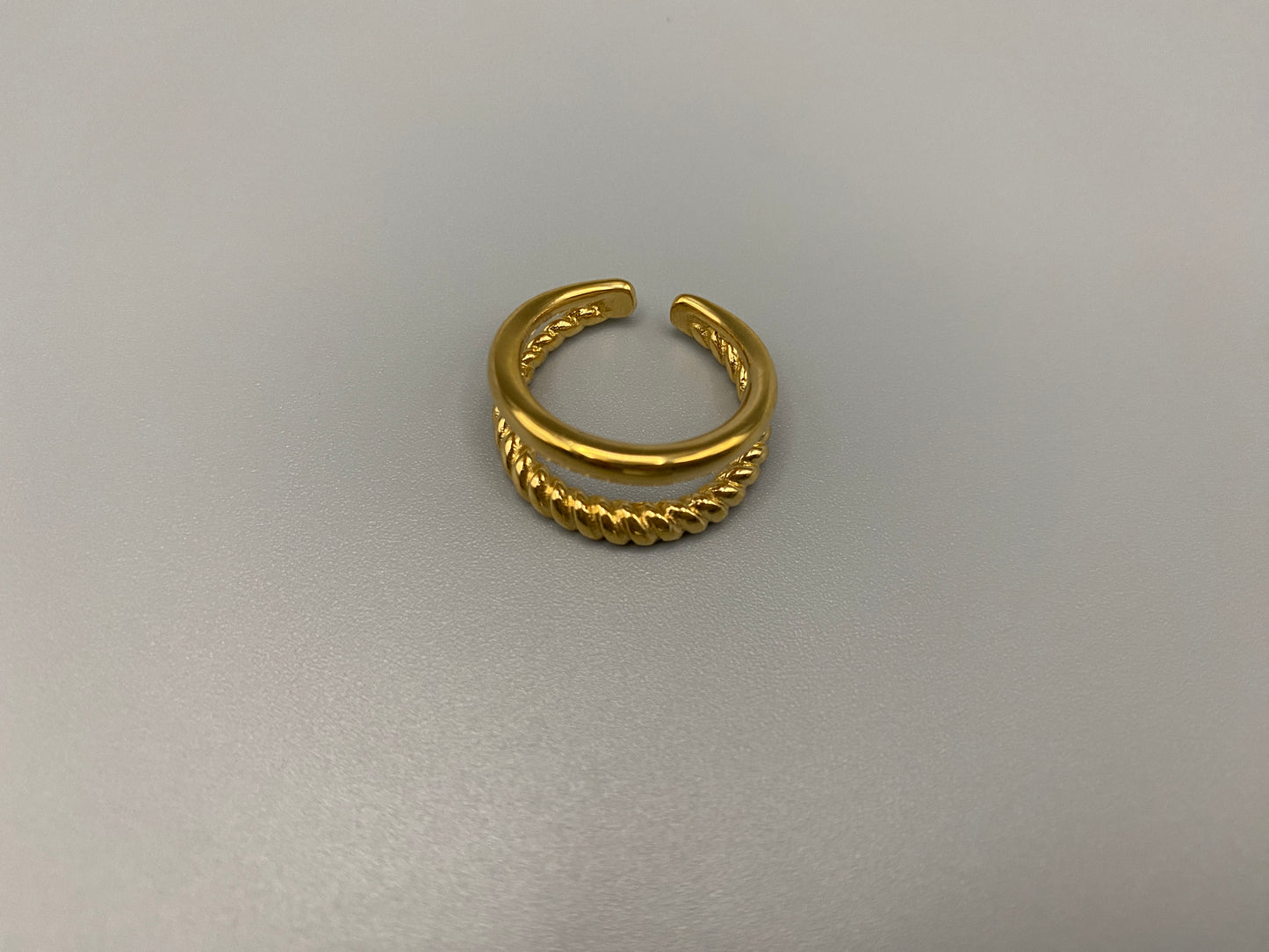 Selene Twin Band Ring Gold: This ring features a unique combination of a textured rope band and a smooth plain band, both gold plated for a luxurious finish. The titanium PVD ensures durability and resistance to wear, while the stainless steel construction adds strength and longevity. The unique twin band design combines elegance and modernity. Available in ring size 7, it is perfect for those who wear this size. Make a statement with this versatile and chic accessory that complements any look.