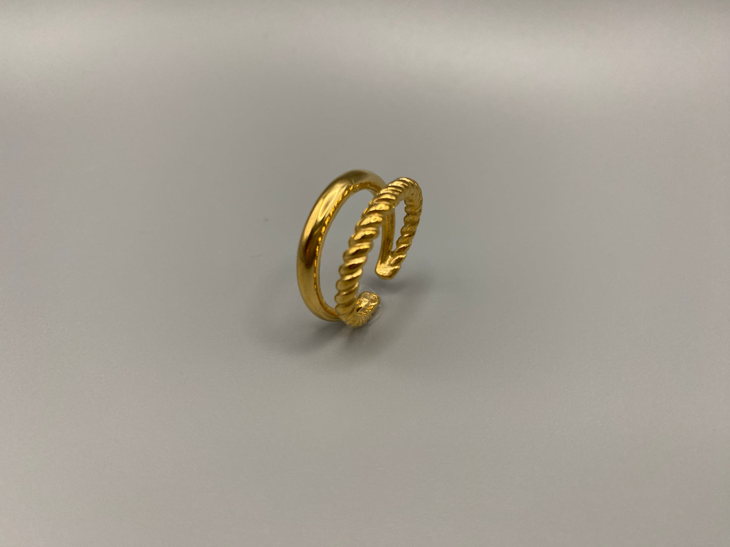 Selene Twin Band Ring Gold: This ring features a unique combination of a textured rope band and a smooth plain band, both gold plated for a luxurious finish. The titanium PVD ensures durability and resistance to wear, while the stainless steel construction adds strength and longevity. The unique twin band design combines elegance and modernity. Available in ring size 7, it is perfect for those who wear this size. Make a statement with this versatile and chic accessory that complements any look.