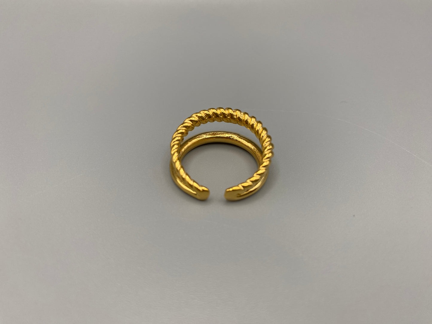 Selene Twin Band Ring Gold: This ring features a unique combination of a textured rope band and a smooth plain band, both gold plated for a luxurious finish. The titanium PVD ensures durability and resistance to wear, while the stainless steel construction adds strength and longevity. The unique twin band design combines elegance and modernity. Available in ring size 7, it is perfect for those who wear this size. Make a statement with this versatile and chic accessory that complements any look.