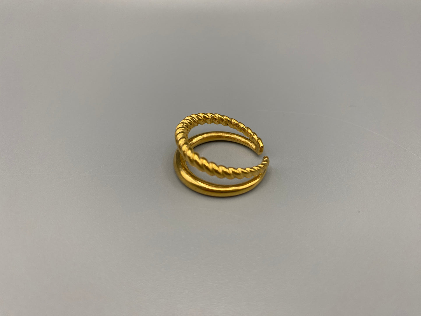 Selene Twin Band Ring Gold: This ring features a unique combination of a textured rope band and a smooth plain band, both gold plated for a luxurious finish. The titanium PVD ensures durability and resistance to wear, while the stainless steel construction adds strength and longevity. The unique twin band design combines elegance and modernity. Available in ring size 7, it is perfect for those who wear this size. Make a statement with this versatile and chic accessory that complements any look.