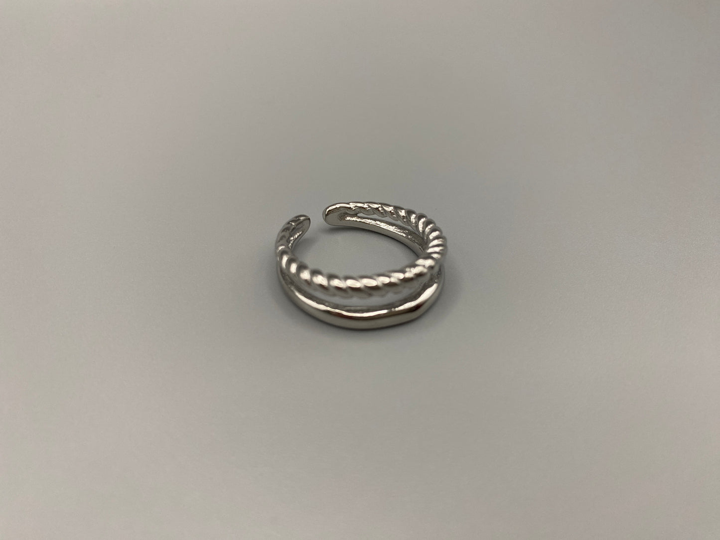 Selene Twin Band Ring Silver: This ring features a unique combination of a textured rope band and a smooth plain band, both gold plated for a luxurious finish. The titanium PVD ensures durability and resistance to wear, while the stainless steel construction adds strength and longevity. The unique twin band design combines elegance and modernity. Available in ring size 7, it is perfect for those who wear this size. Make a statement with this versatile and chic accessory that complements any look.