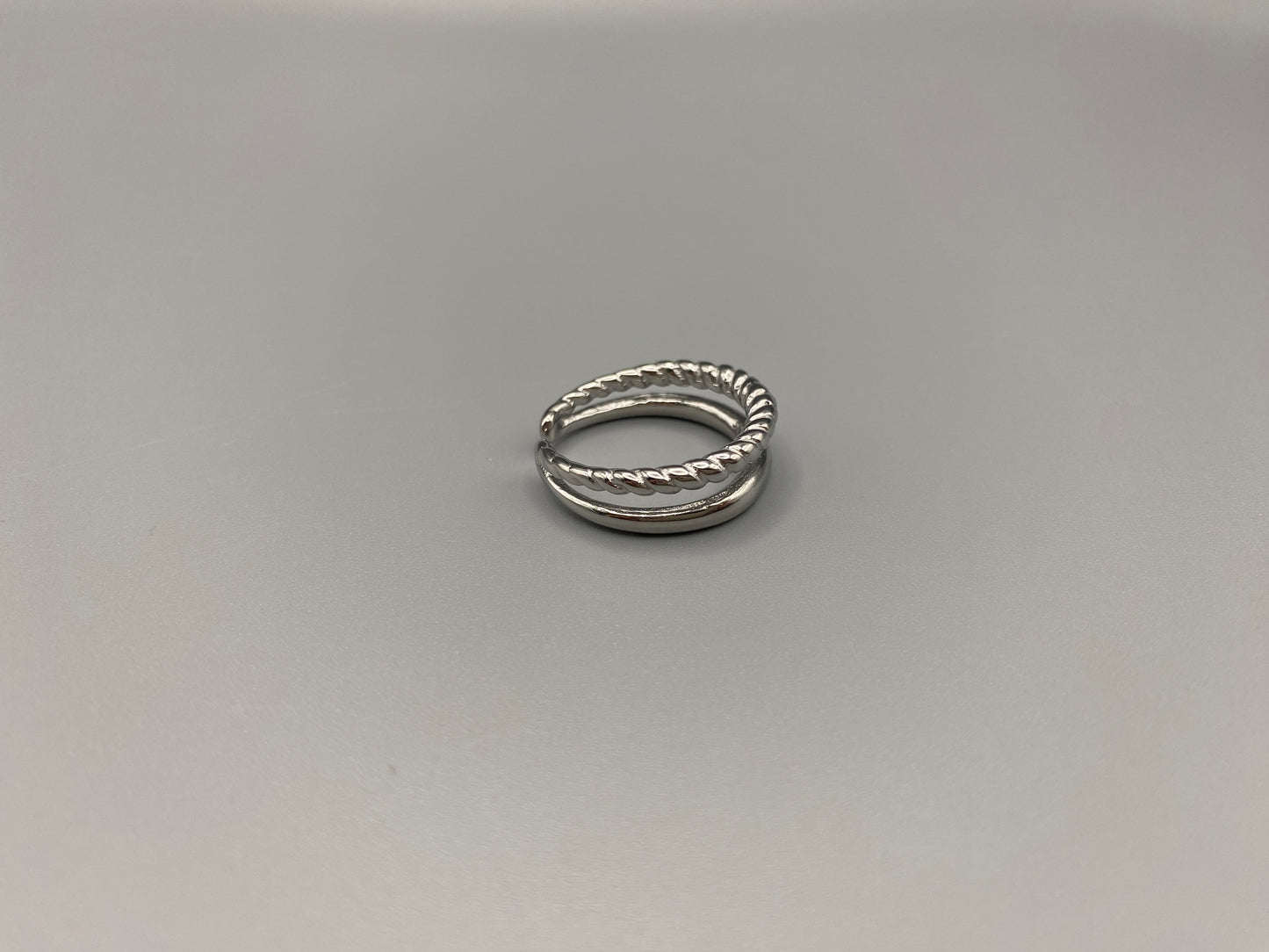 Selene Twin Band Ring Silver: This ring features a unique combination of a textured rope band and a smooth plain band, both gold plated for a luxurious finish. The titanium PVD ensures durability and resistance to wear, while the stainless steel construction adds strength and longevity. The unique twin band design combines elegance and modernity. Available in ring size 7, it is perfect for those who wear this size. Make a statement with this versatile and chic accessory that complements any look.