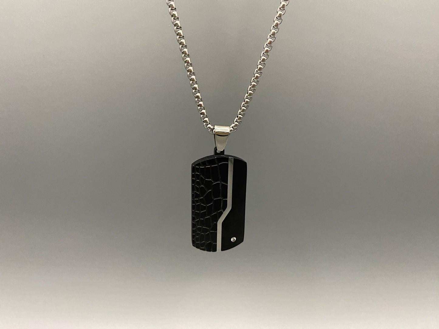 “Sentinel Black Pendant Stainless Steel Men’s Dog Necklace featuring a sleek black finish and a cross pattern, displayed on a strand chain.”