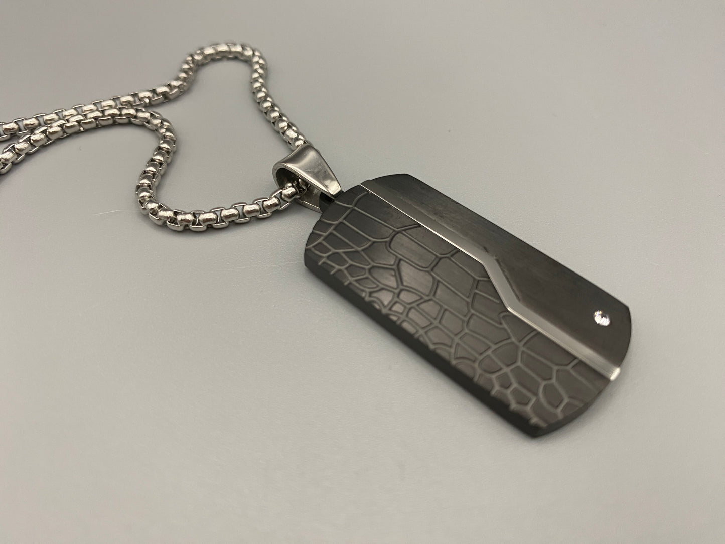 “Sentinel Black Pendant Stainless Steel Men’s Dog Necklace featuring a sleek black finish and a cross pattern, displayed on a strand chain.”