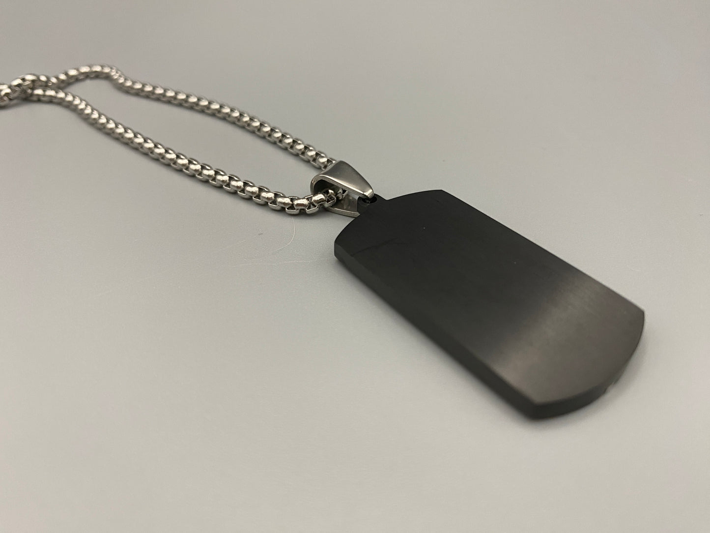“Sentinel Black Pendant Stainless Steel Men’s Dog Necklace featuring a sleek black finish and a cross pattern, displayed on a strand chain.”
