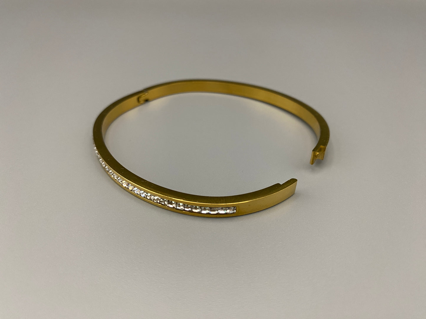 “Simone Encrusted Bangle in gold with 18K gold plating and gemstone inlay, offering a radiant and luxurious finish. Durable construction ensures long-lasting wear and tarnish resistance. Perfect for both everyday wear and special occasions.”