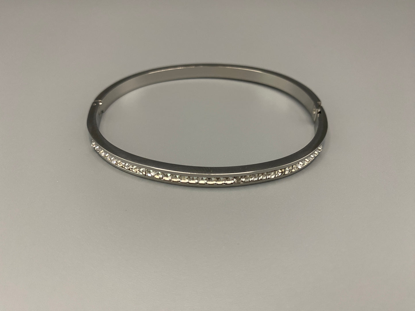 “Simone Encrusted Bangle in silver with silver plating and gemstone inlay, offering a radiant and luxurious finish. Durable construction ensures long-lasting wear and tarnish resistance. Perfect for both everyday wear and special occasions.”