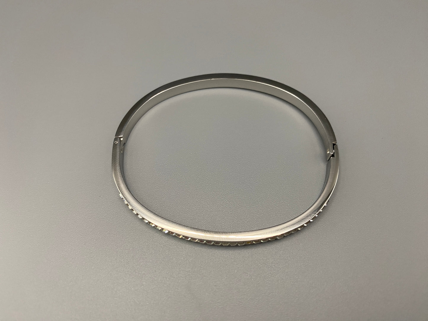“Simone Encrusted Bangle in silver with silver plating and gemstone inlay, offering a radiant and luxurious finish. Durable construction ensures long-lasting wear and tarnish resistance. Perfect for both everyday wear and special occasions.”