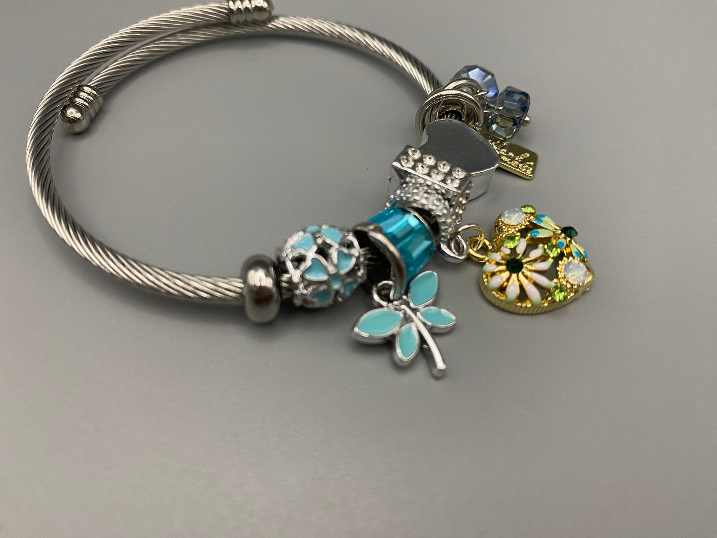 “Stellar Charm Bracelet in blue with playful charms including a heart, butterfly, and cube, crafted from high-quality stainless steel. Suitable for both women and kids, making it a perfect gift for any occasion.”