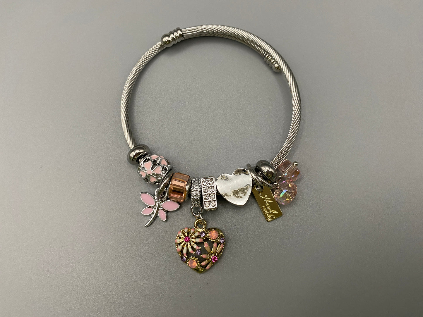 “Stellar Charm Bracelet in pink with playful charms including a heart, butterfly, and cube, crafted from high-quality stainless steel. Suitable for both women and kids, making it a perfect gift for any occasion.”
