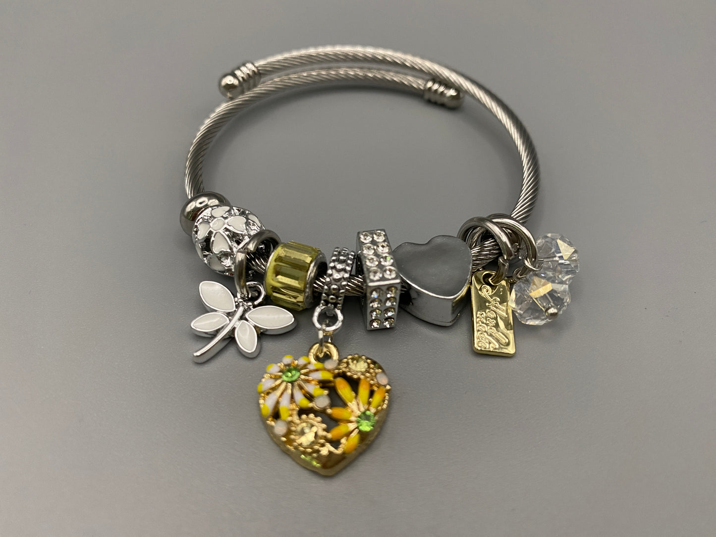 “Stellar Charm Bracelet in yellow with playful charms including a heart, butterfly, and cube, crafted from high-quality stainless steel. Suitable for both women and kids, making it a perfect gift for any occasion.”