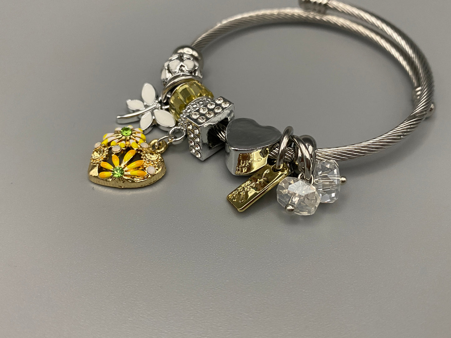 “Stellar Charm Bracelet in yellow with playful charms including a heart, butterfly, and cube, crafted from high-quality stainless steel. Suitable for both women and kids, making it a perfect gift for any occasion.”