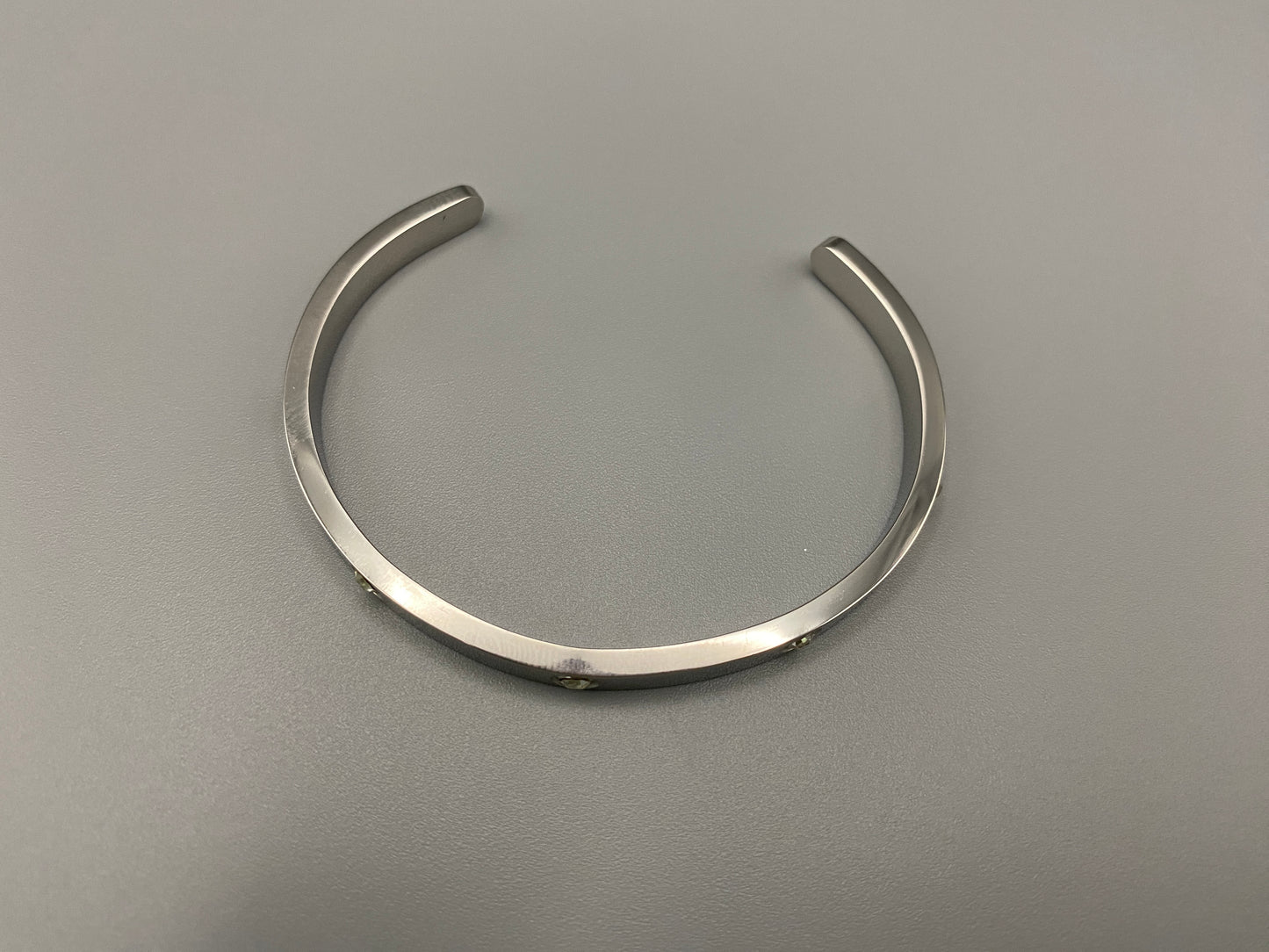“Lucy Bangle in silver with silver plating and gemstone inlay, offering a radiant and luxurious finish. Durable construction ensures long-lasting wear and tarnish resistance. Perfect for both