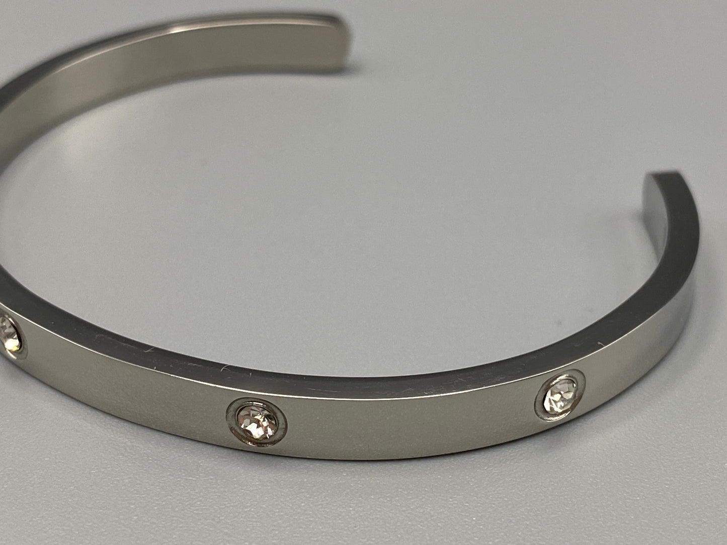 “Lucy Bangle in silver with silver plating and gemstone inlay, offering a radiant and luxurious finish. Durable construction ensures long-lasting wear and tarnish resistance. Perfect for both